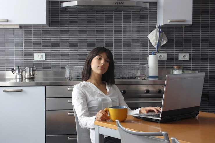Foto hübsche frau, die an einem laptop in der küche arbeitet