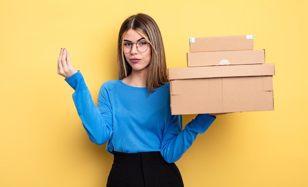 Hübsche Frau, die Capice oder Geldgeste macht und Ihnen sagt, dass Sie das Konzept der Paketboxen bezahlen sollen