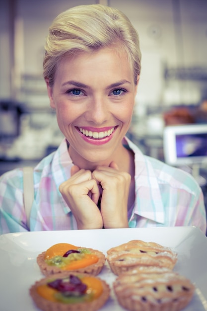 Foto hübsche frau, die eine fruchttorte betrachtet