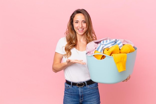 Hübsche Frau, die fröhlich lächelt, sich glücklich fühlt und ein Konzept zeigt und Kleidung wäscht.