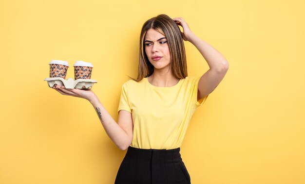 Hübsche Frau, die glücklich lächelt und träumt oder zweifelt. kaffee konzept zum mitnehmen