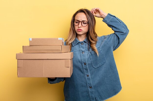 Hübsche Frau, die glücklich lächelt und träumt oder zweifelt. Paketboxen-Konzept