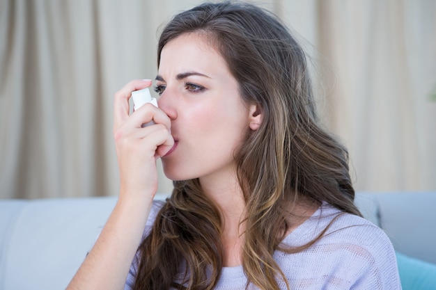 Hübsche Frau, die ihren Inhalator nimmt