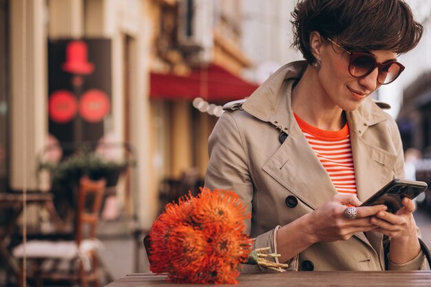 Hübsche Frau, die im Café in Chinatown sitzt und am Telefon spricht