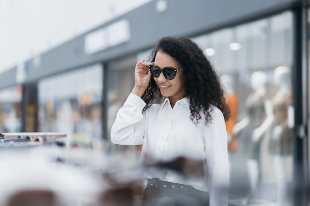 Hübsche Frau, die im Einkaufszentrum eine Sonnenbrille anprobiert