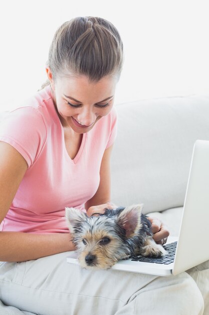 Hübsche Frau, die Laptop mit ihrem Yorkshire-Terrier verwendet