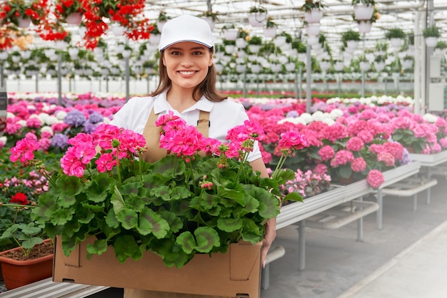 Hübsche Frau, die Pappschachtel mit schönen rosa Blumen hält