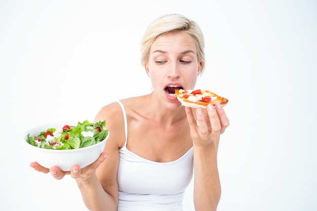 Hübsche Frau, die Pizza eher den Salat essend entscheidet