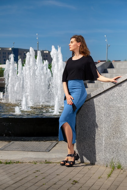 Hübsche Frau, die Rest nahe dem Brunnen hat