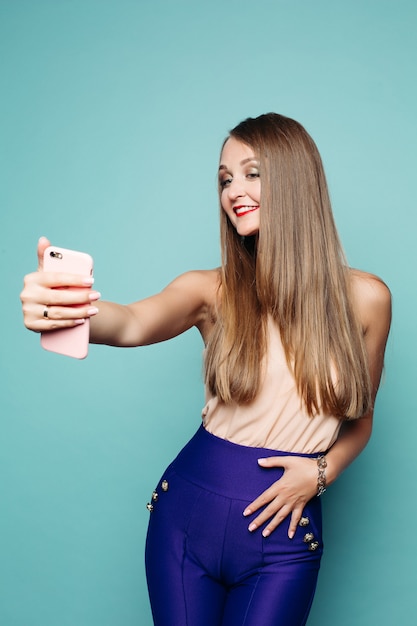 Hübsche Frau, die selfie über Handy über grünem Hintergrund nimmt.