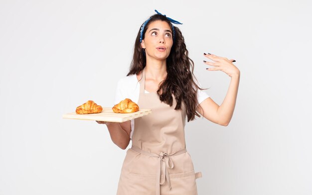 Hübsche Frau, die sich gestresst, ängstlich, müde und frustriert fühlt und ein Croissants-Tablett hält