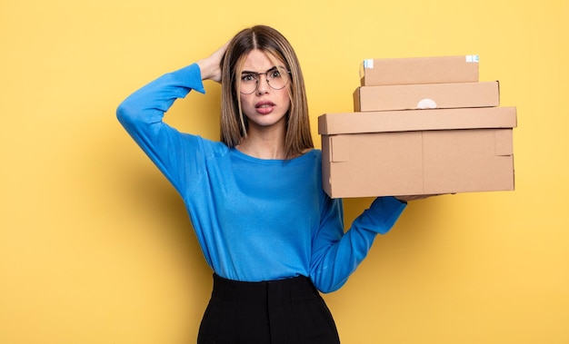 Hübsche Frau, die sich gestresst, ängstlich oder verängstigt fühlt, mit den Händen auf dem Kopf verpackt Boxen Konzept