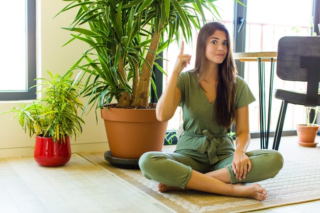 Hübsche frau, die sich wie ein genie fühlt, das stolz den finger in der luft hält, nachdem sie eine großartige idee verwirklicht hat und eureka sagt