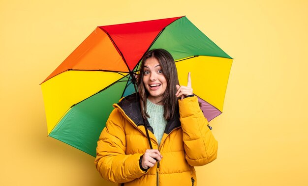 Hübsche Frau, die sich wie ein glückliches und aufgeregtes Genie fühlt, nachdem sie ein Ideenwinter- und Regenschirmkonzept verwirklicht hat