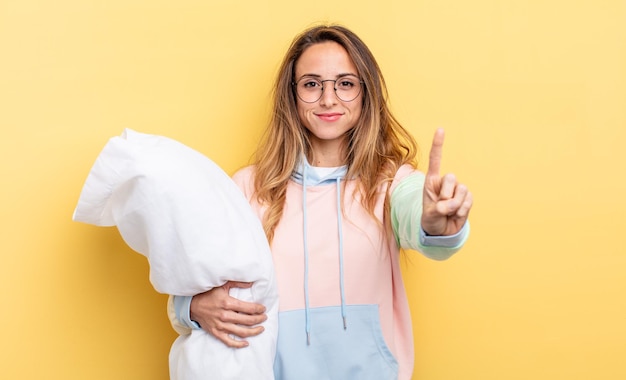 Hübsche Frau, die stolz und selbstbewusst lächelt und die Nummer eins macht. Pyjama-Konzept