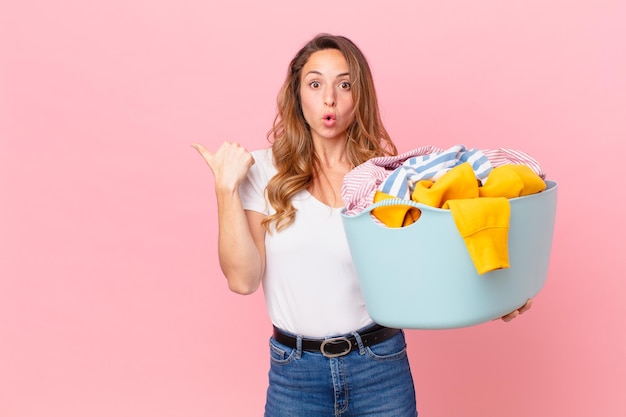 Hübsche Frau, die ungläubig aussieht und Kleidung wäscht.