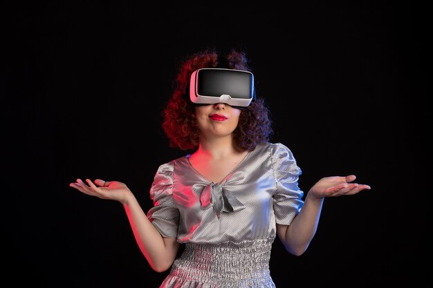 Hübsche Frau, die Virtual-Reality-Headset auf dunkler Oberfläche trägt