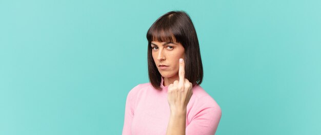 hübsche Frau, die wütend, genervt, rebellisch und aggressiv ist, den Mittelfinger zeigt, sich wehrt