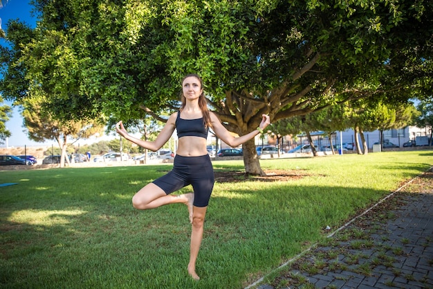 Hübsche Frau, die Yoga im Morgenpark tut Gesunder Lebensstil im Freien Konzeption Sport Frau Naturporträt Übungen Gesunder Lebensstil