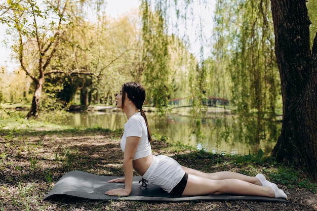 Hübsche Frau, die Yogaübungen im Park macht