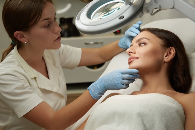 Hübsche Frau erhalten kosmetologische Verfahren von professionellen Therapeuten in der modernen Klinik