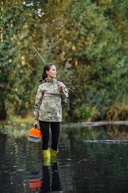 Hübsche Frau fischt auf dem Fluss