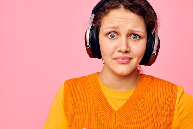 Hübsche Frau Grimasse Kopfhörer Unterhaltung Emotionen Musik rosa Hintergrund unverändert