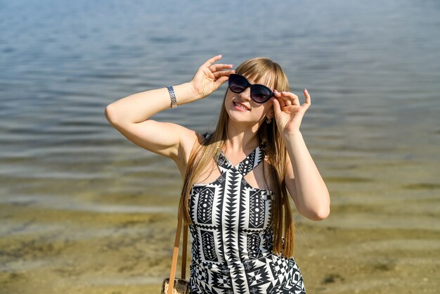 Hübsche Frau im Kleid nahe See, Sommerzeit