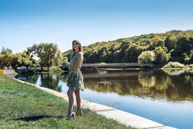 Hübsche Frau im Kleid stand am See und entspannte sich in der Natur