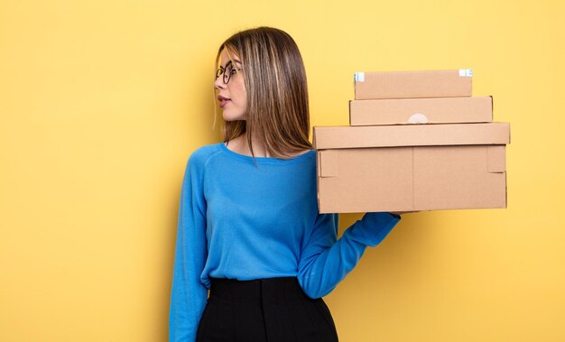 Hübsche Frau in der Profilansicht, die das Konzept der Paketboxen denkt, sich vorstellt oder träumt