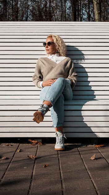 Hübsche Frau in der Sonnenbrille auf Bank am Herbstpark allein, Lebensstilmenschenkonzept