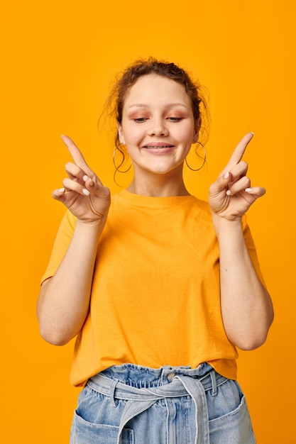 Hübsche Frau in einem gelben T-Shirt, das Emotionen aufwirft, isolierte Hintergründe unverändert