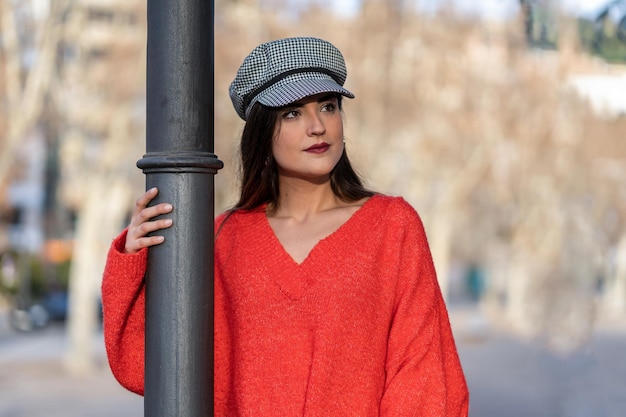 Hübsche Frau in schwarz-weißem Hut mit rotem Pullover