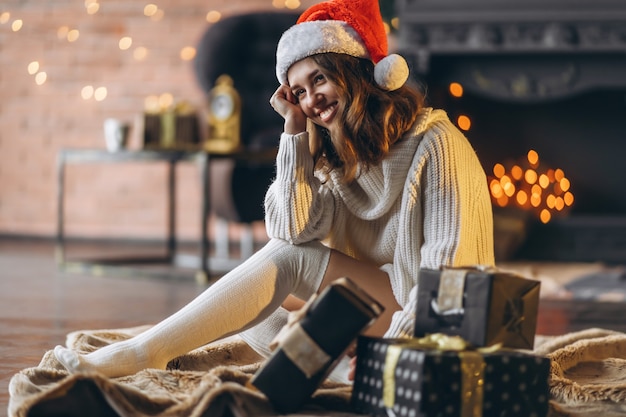 Hübsche Frau in warmem Pullover, Socken und Weihnachtsmütze