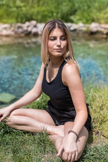 Hübsche Frau macht Yoga-Meditation in der Nähe von See, im Freien. gesunder Lebensstil