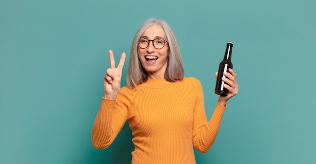 Hübsche Frau mit grauem Haar, die ein Bier trinkt