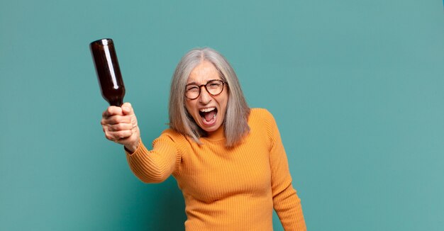 Hübsche Frau mit grauem Haar, die ein Bier trinkt