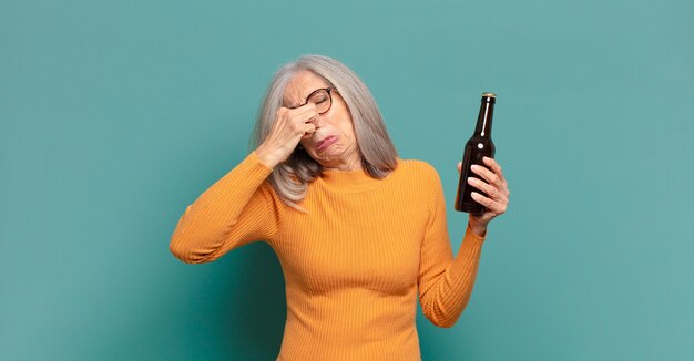 Foto hübsche frau mit grauem haar, die ein bier trinkt