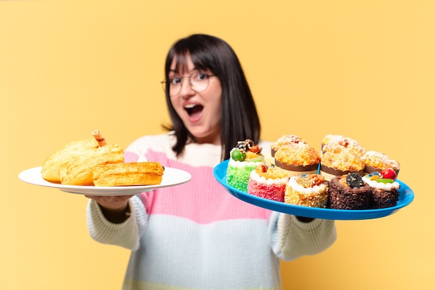 Hübsche Frau mit Kuchen und Cupcakes