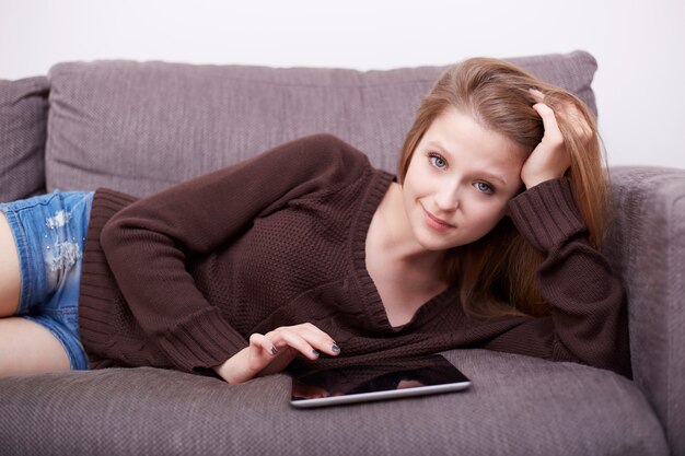 Hübsche Frau mit Laptop auf Sofa