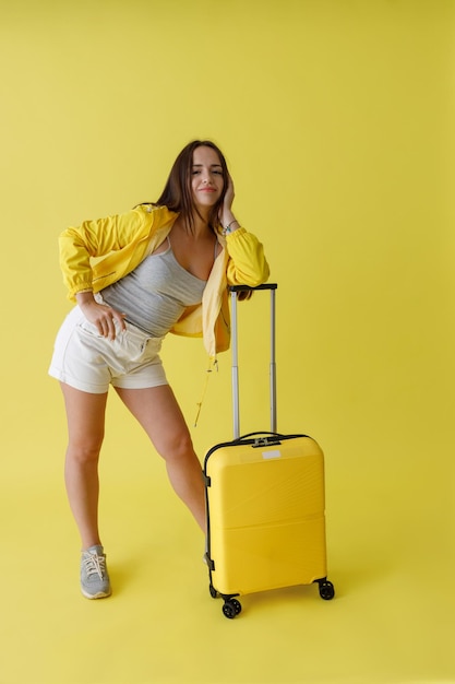 Hübsche Frau mit Reisetasche, die im Studio steht