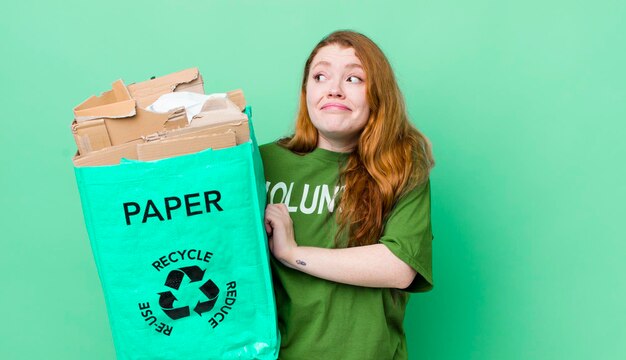 Hübsche Frau mit rotem Kopf, die sich verwirrt und unsicher beim Recycling-Konzept fühlt