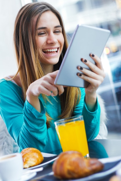 Hübsche Frau mit Tablet beim Frühstück im Coffee-Shop