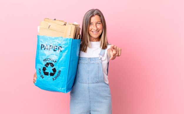 Hübsche Frau mittleren Alters, die auf die Kamera zeigt, die Ihr Recycling-Kartonkonzept wählt