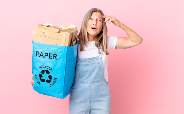 Hübsche Frau mittleren Alters, die glücklich, erstaunt und überrascht aussieht, Recycling-Kartonkonzept