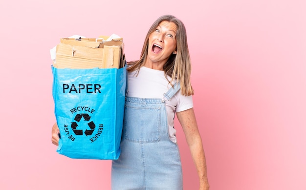 Foto hübsche frau mittleren alters, die glücklich und angenehm überrascht aussieht recycling-karton-konzept