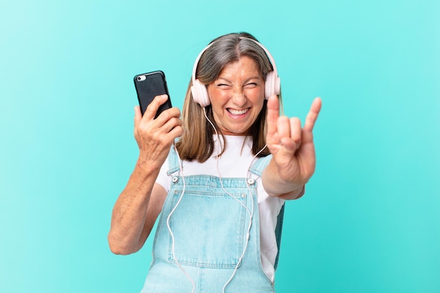 Hübsche Frau mittleren Alters, die Musik mit Kopfhörern hört