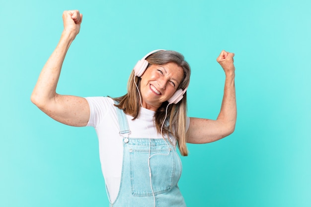 Hübsche frau mittleren alters, die musik mit kopfhörern hört