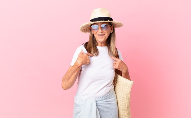 Hübsche Frau mittleren Alters, die sich glücklich fühlt und mit einem aufgeregten auf sich selbst zeigt. Sommerkonzept