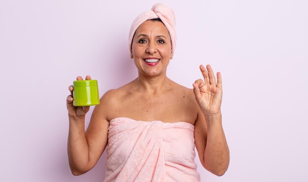 Hübsche Frau mittleren Alters, die sich glücklich fühlt und Zustimmung mit einer Geste zeigt. dusch- und haarproduktkonzept
